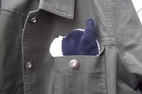 Smudge Dog peeking out of a pocket of a jean jacket.