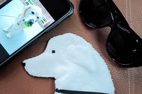 Showing scale of Smudge Dog with two of the many items it can clean and polish: smart phone and eye glasses.