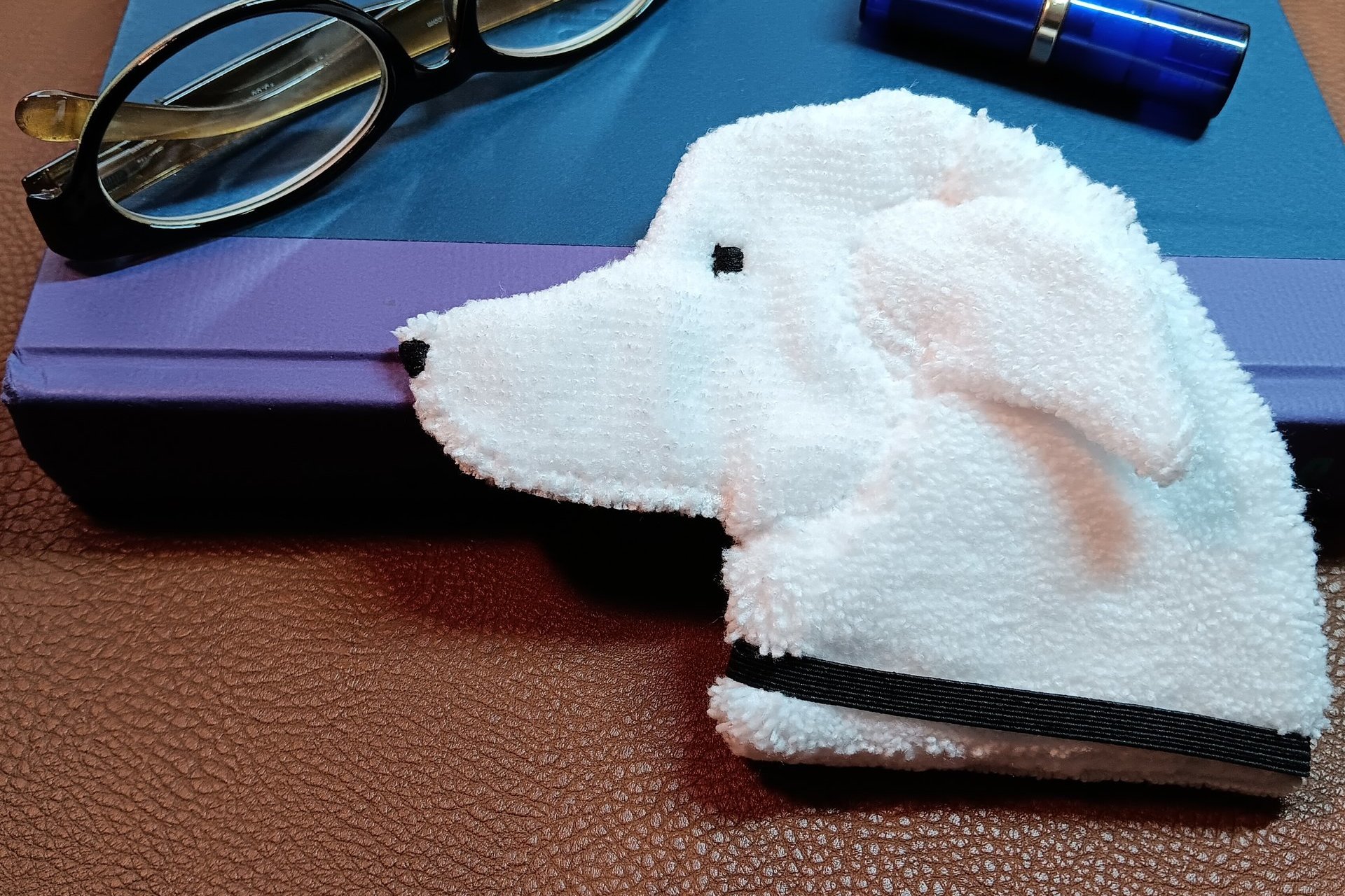 Smudge dog waiting to be used as a bookmark next to a book with glasses